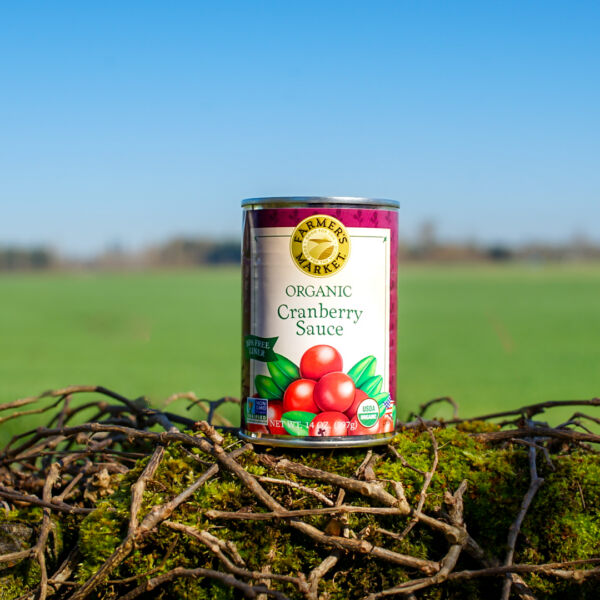a single can of organic cranberry sauce with a farm back drop